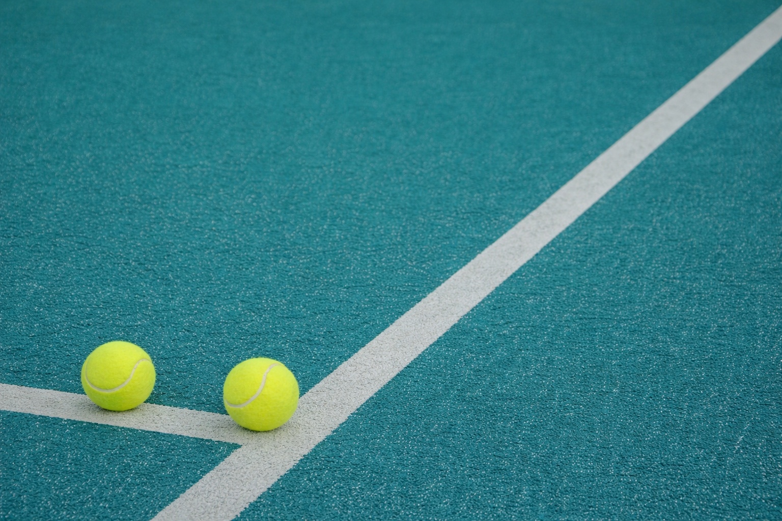Two padel balls on a teal court